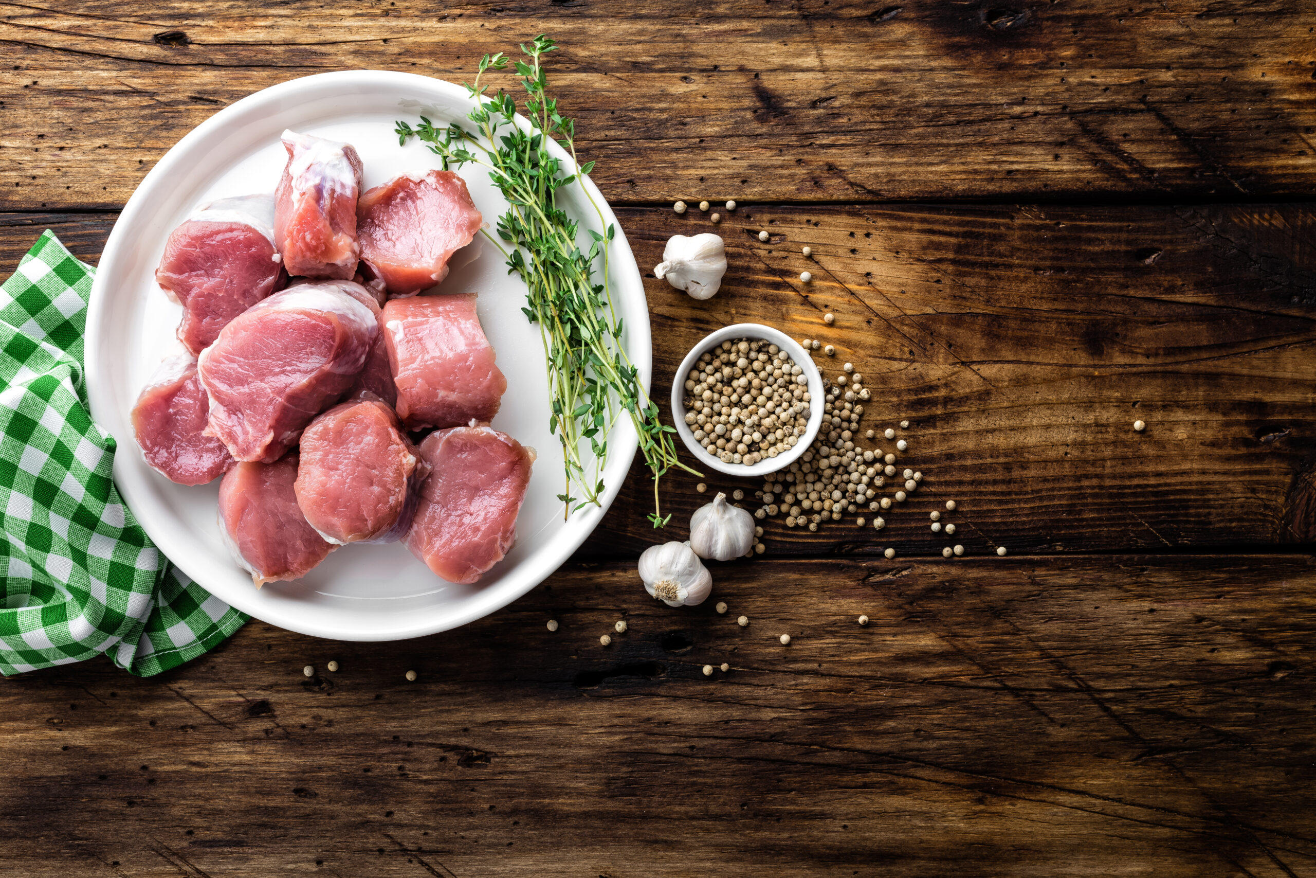 Fresh raw pork tenderloin, chopped meat on dark wooden rustic background, top view